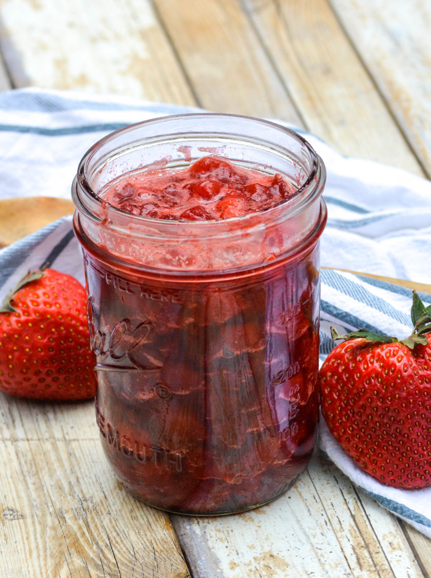 quick and easy homemade strawberry sauce in a glass mason jar with fresh berries on the side