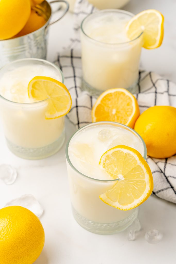 creamy lemonade served in two glasses over ice with lemon slices on the rim of the glasses for garnish