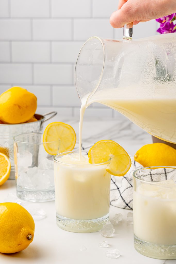 creamy lemonade being poured into an ice filled glass