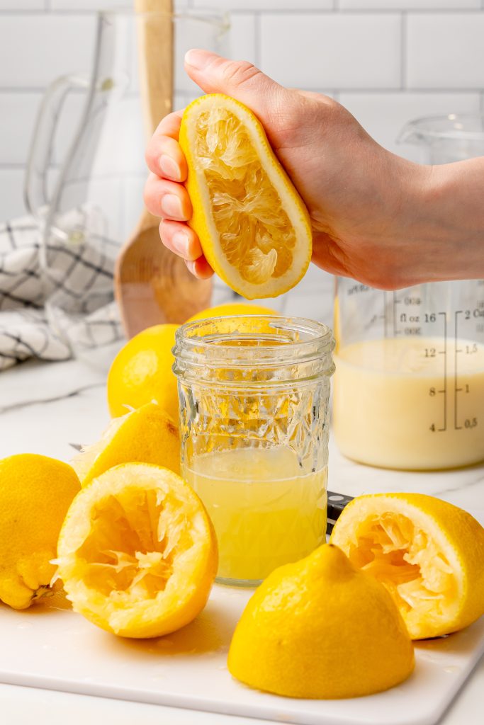 fresh lemon juice being squeezed into a clear glass jar