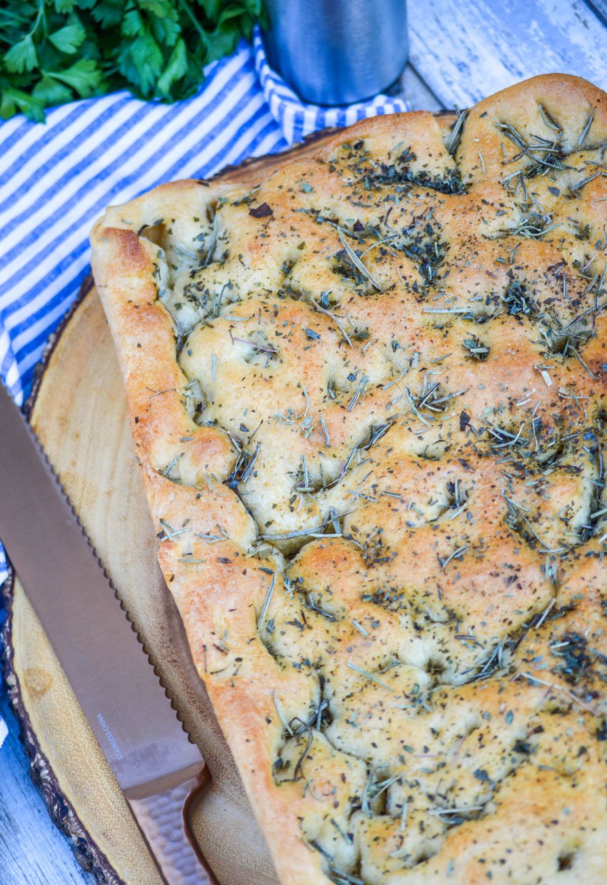 quick and easy focaccia bread topped with rosemary on a wooden cutting board