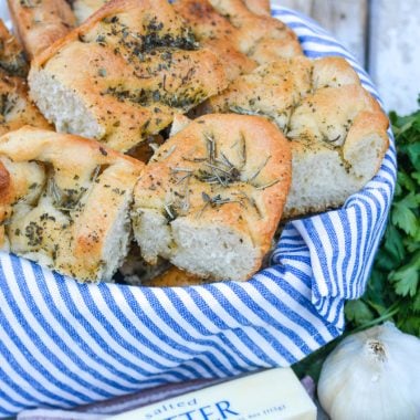 shortcut focaccia bread cut into pieces and stacked in a blue cloth lined bread basket