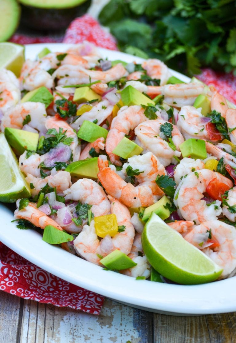 copycat costco shrimp ceviche in a white oval bowl beside a bunch of fresh cilantro