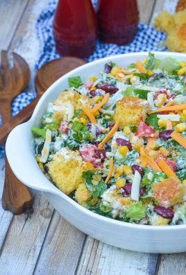 Southern cornbread salad in a white bowl next to wooden salad servers