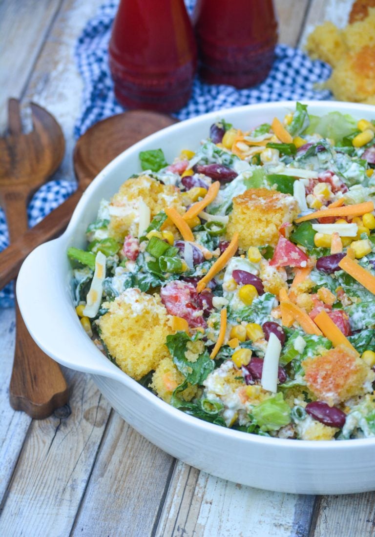 Southern cornbread salad in a white bowl next to wooden salad servers