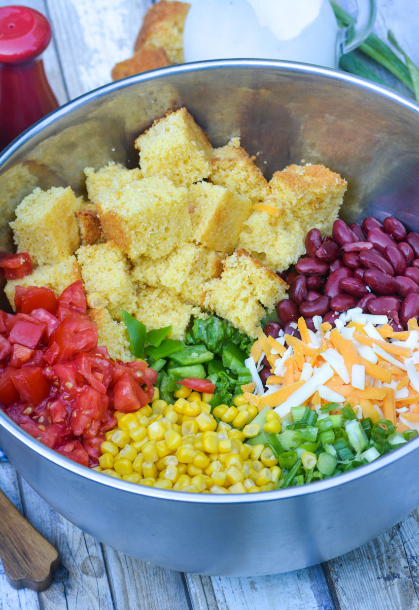 all the ingredients needed to make a cornbread salad in a large silver mixing bowl