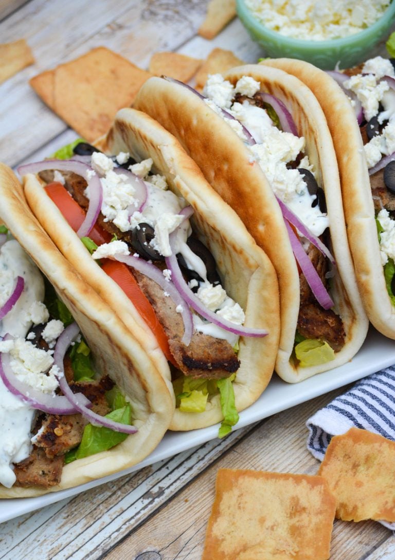 homemade gyros arranged in a row on a white platter