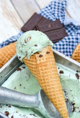 a scoop of no churn mint chocolate chip ice cream in a sugar cone resting on the edge of a metal loaf pan