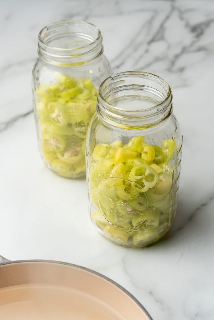 sliced banana peppers in two glass mason jars