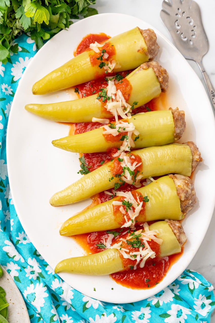 sausage stuffed banana peppers on a white serving platter