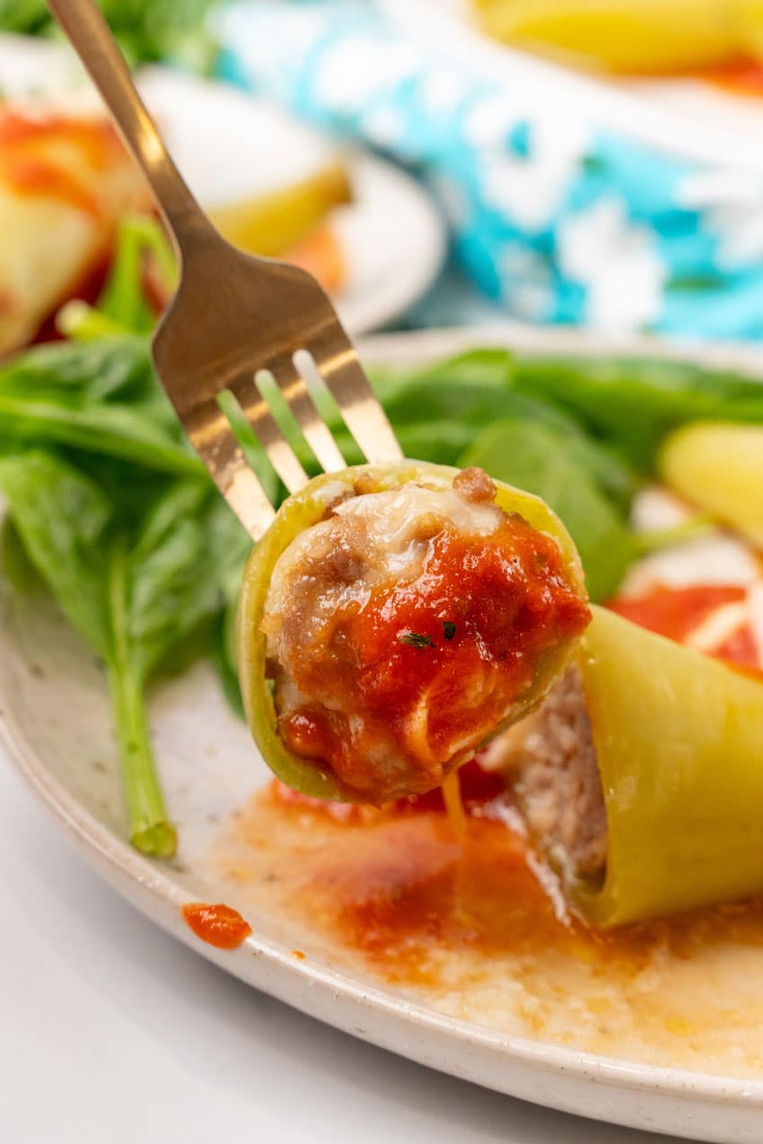 sausage stuffed banana peppers cut open to reveal the filling on a white plate