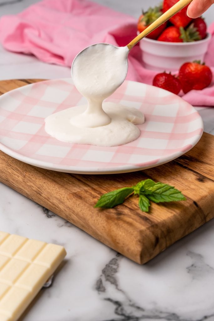 whipped cream sauce being ladled onto a flat dinner plate