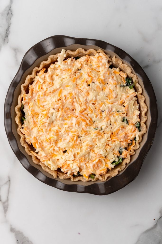 a cheesy mayo mixture spread over veggies in a deep dish pie crust