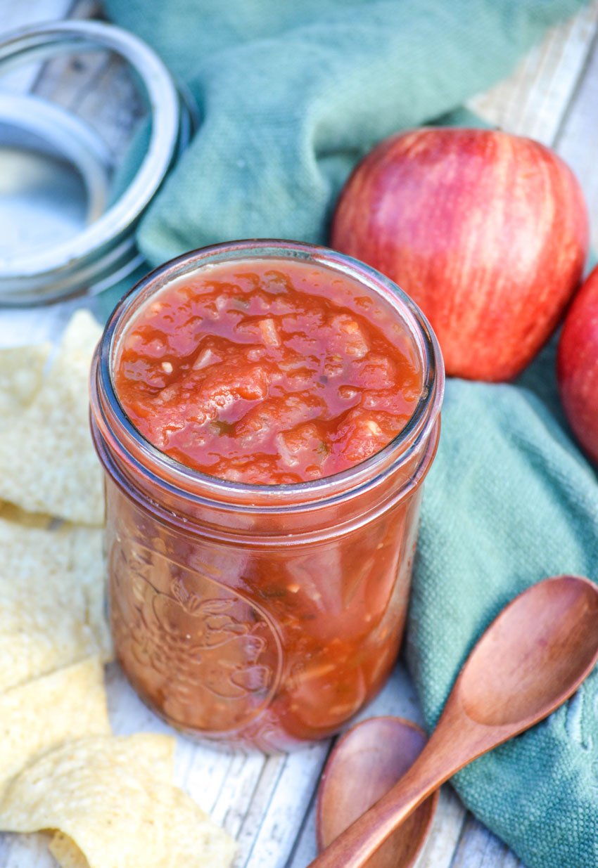 apple salsa in a glass mason jar with chips and wooden spoons on the side