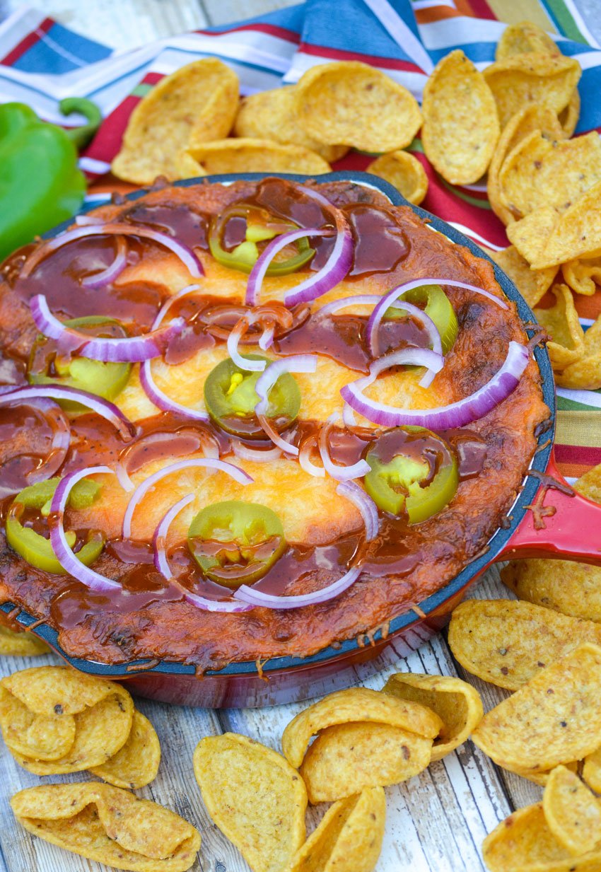 cheesy barbecue sauce topped pulled pork dip in a red enameled cast iron skillet