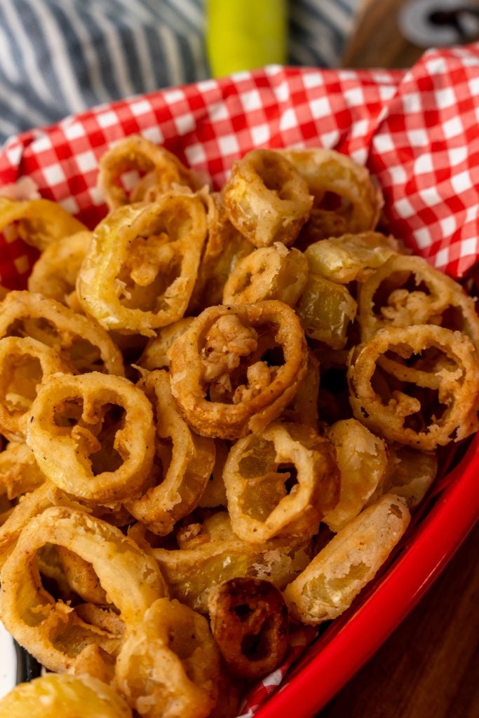 fried banana pepper rings in a paper lined red plastic basket