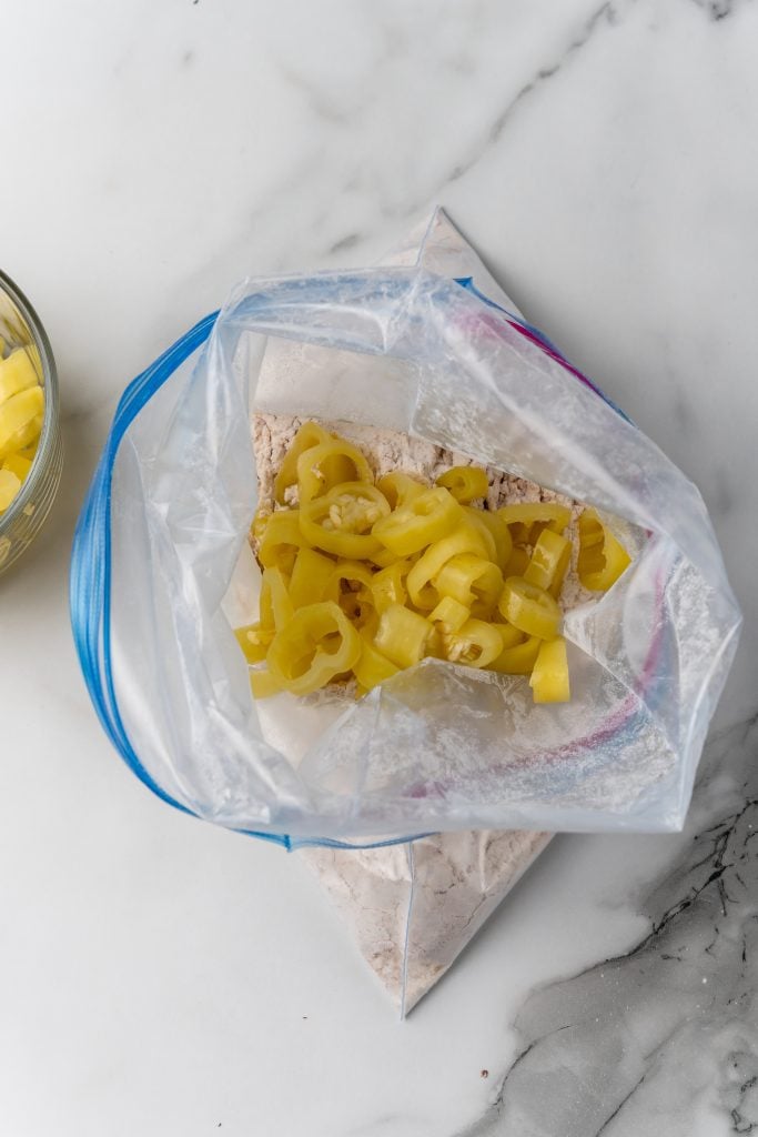 pickled banana pepper rings in a large ziplocking bag with seasoned flour