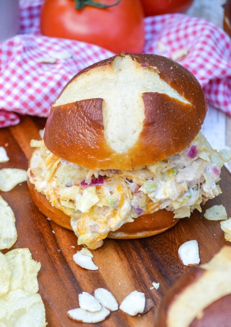 a hot chicken salad sandwich on a wooden cutting board