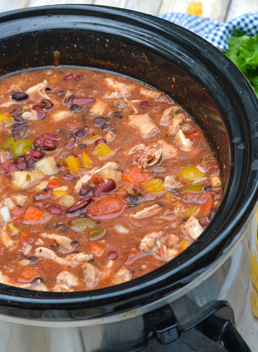 a black crockpot filled with slow cooker jerk chicken chili