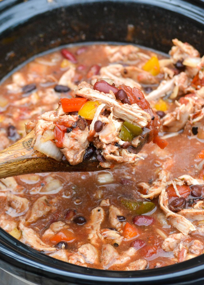 a wooden spoon holding up a spoonful of slow cooker jerk chicken chili