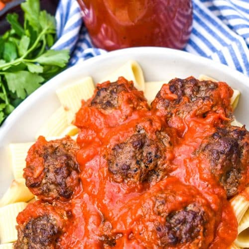 smoked meatballs in red sauce over cooked pasta in a white bowl