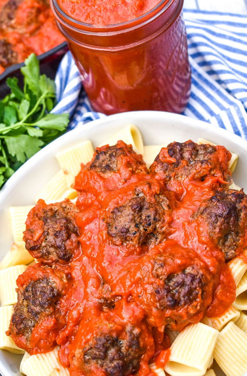 smoked meatballs in red sauce over cooked pasta in a white bowl