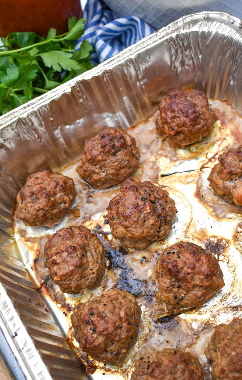 smoked meatballs arranged in rows in an aluminum baking dish