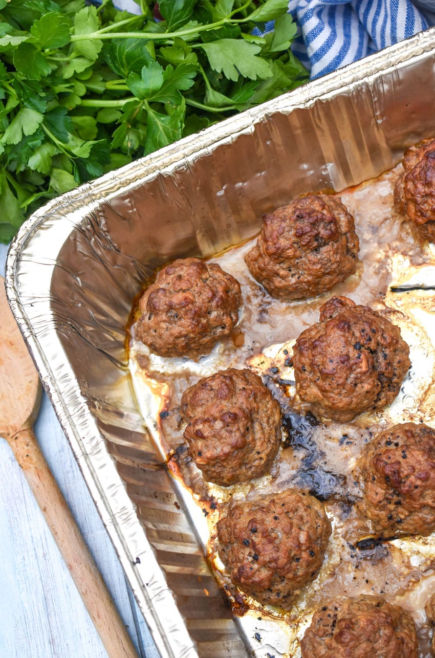 smoked meatballs arranged in rows in an aluminum baking pan