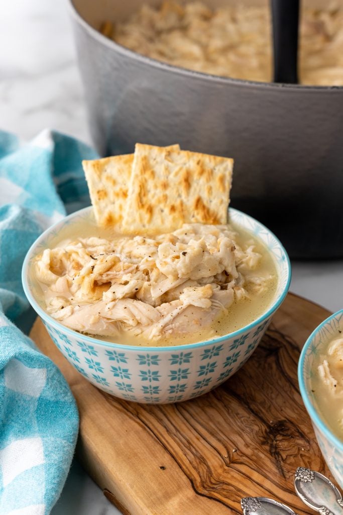 chicken mull in a small blue bowl with saltine crackers