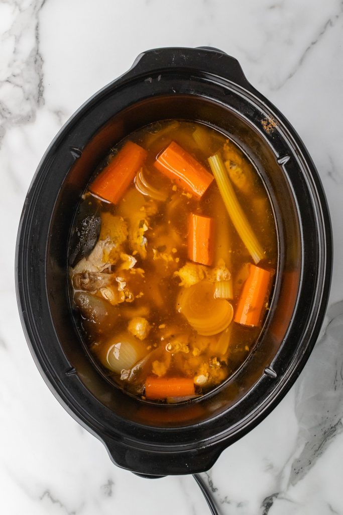 cooked ingredients and homemade bone broth in a black crockpot