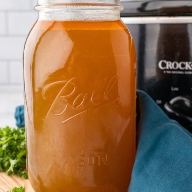 crockpot chicken broth in a tall glass mason jar