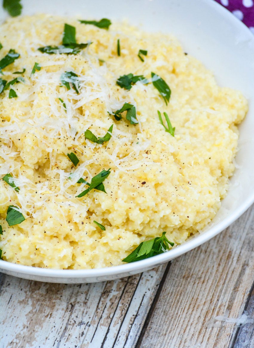 Nonna's creamy pastina recipe with egg in a white bowl topped with fresh herbs and shaved parmesan cheese
