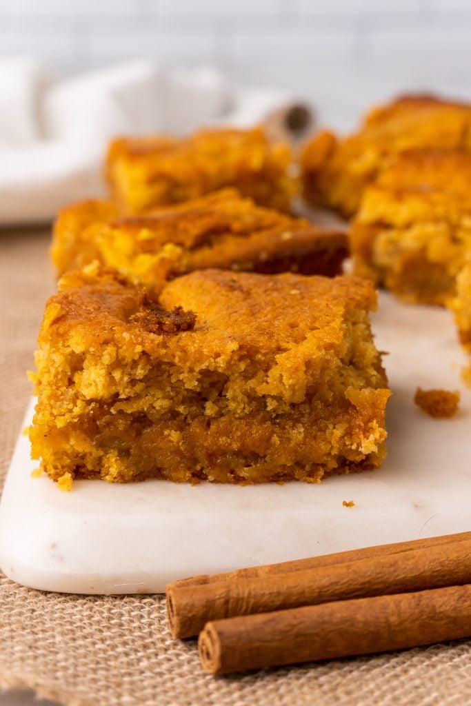 squares of pumpkin gooey butter bars on a white cutting board