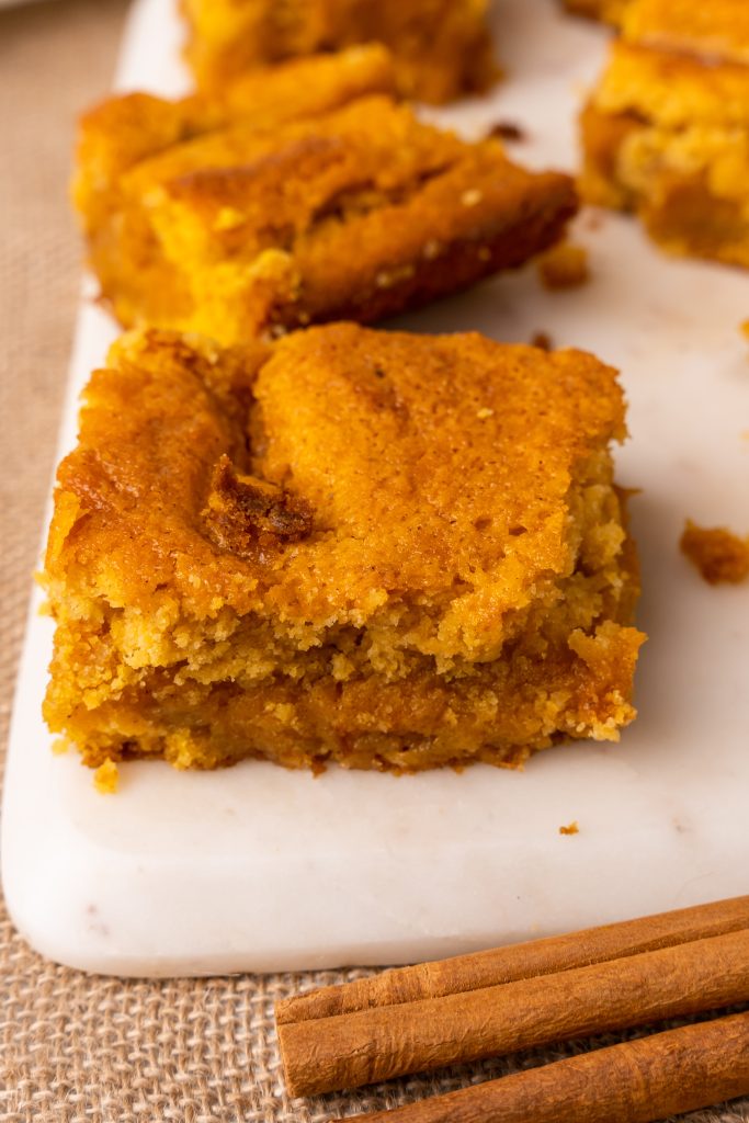 squares of pumpkin gooey butter bars on a white cutting board