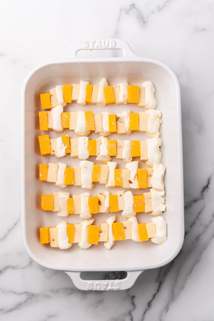 cheese slices arranged in rows to fill a white casserole dish