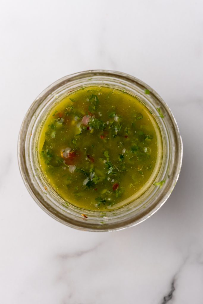 a cheese marinade made of olive oil, herbs, and spices mixed together in a small glass jar