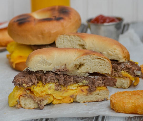 copycat Mcdonalds steak egg and cheese bagel sandwich cut in half and served on a sheet of white parchment paper