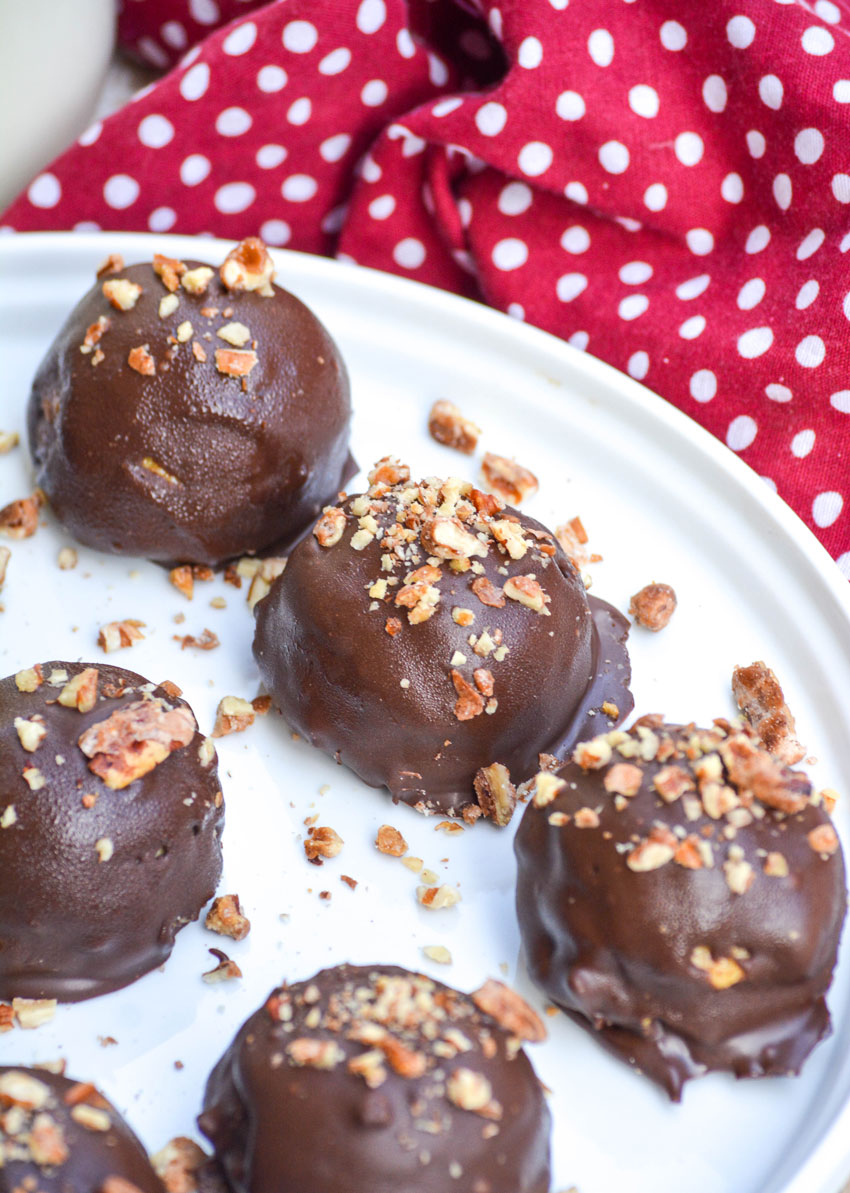 pecan topped chocolate covered pumpkin pie truffles in rows on a white plate