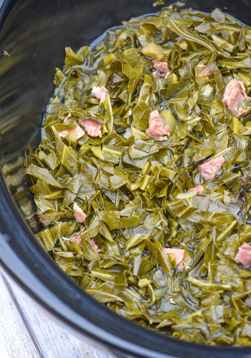classic southern style collard greens cooked down in a black crockpot with bits of country ham