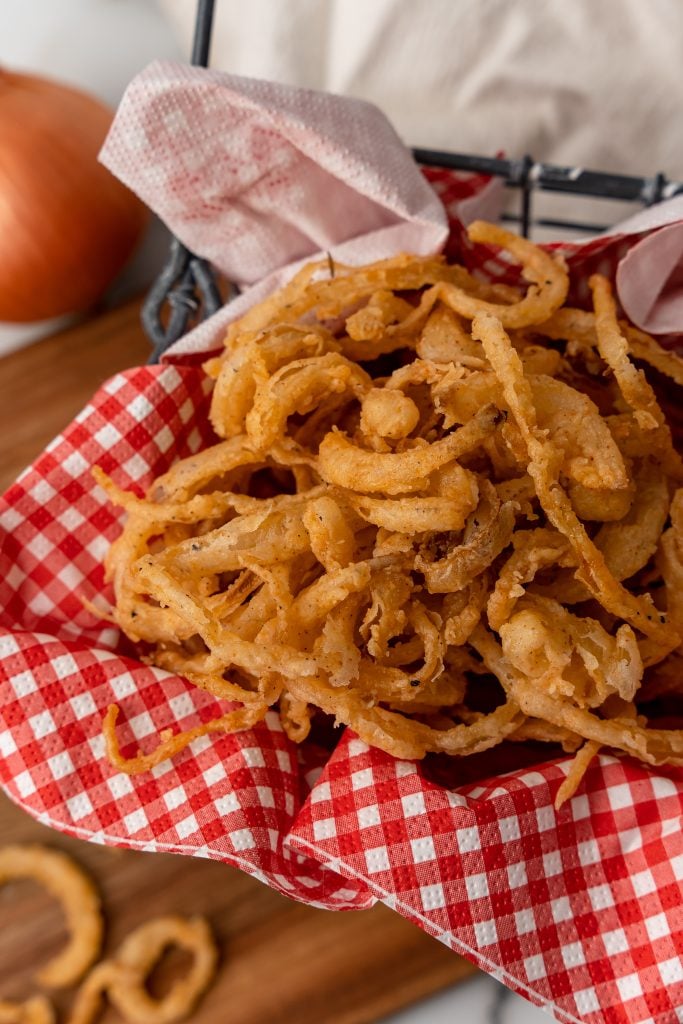 fried crispy onion straws in a red paper lined basked
