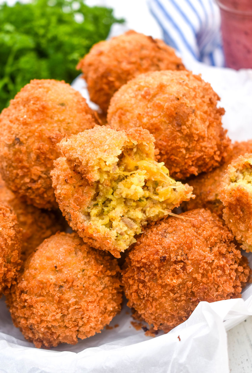 a pile of crispy cornbread dressing fritters on a parchment paper lined bowl