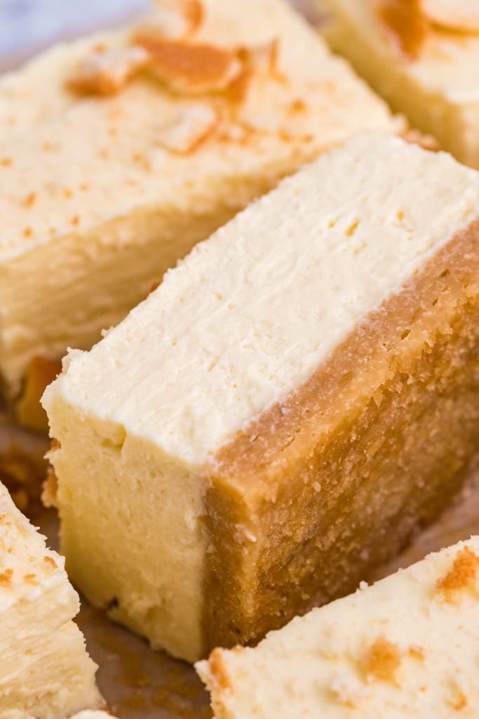 a sliced banana cheesecake bar flipped on it's side to show the creamy filling and blondie crust