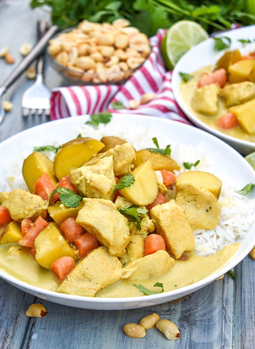 slow cooker chicken curry over white rice in a shallow white bowl