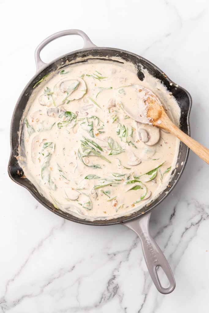 champagne cream sauce with spinach in a large black skillet