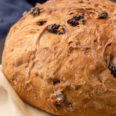 a baked loaf of cranberry walnut bread on parchment paper