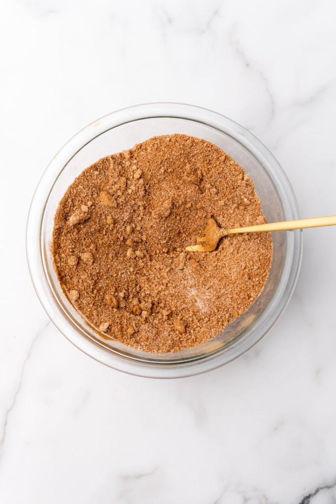 mixed cinnamon and sugar in a glass mixing bowl with a gold fork