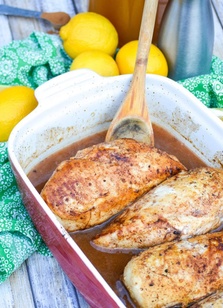 a wooden spoon resting in a casserole dish with pieces of little house on the prairie cinnamon chicken breasts