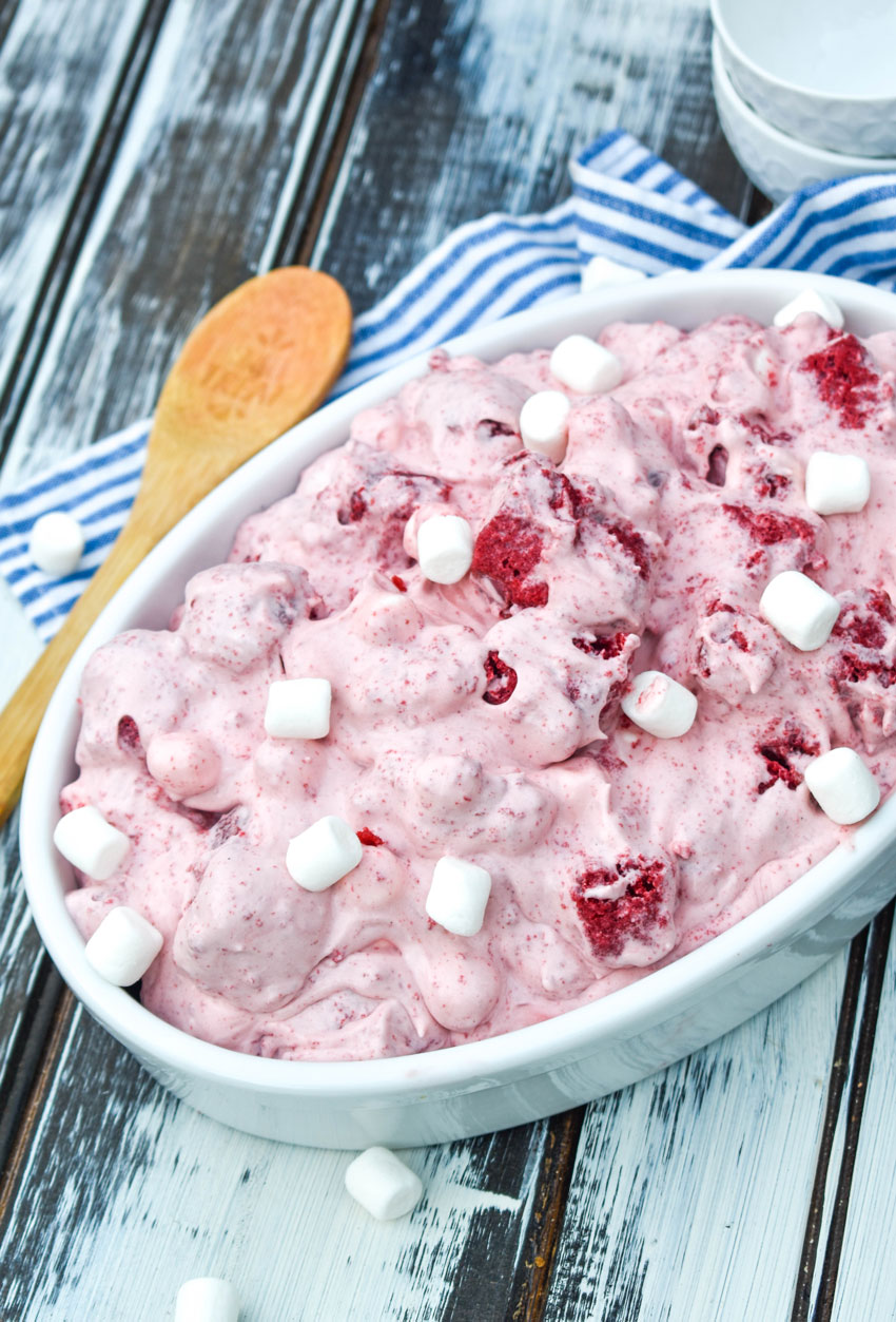 red velvet fluff salad topped with miniature marshmallows in a shallow white oval serving bowl