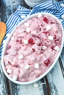 red velvet fluff salad topped with miniature marshmallows in a shallow white oval serving bowl