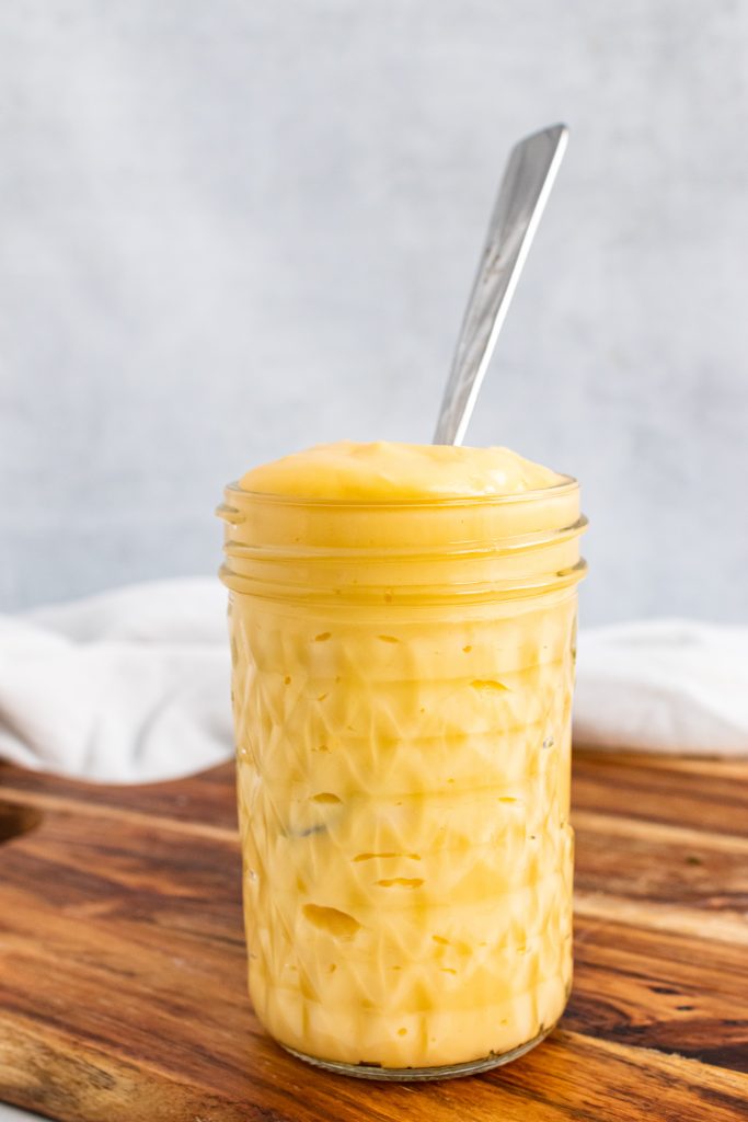 Homemade Condensed Cheddar Cheese Soup in a glass mason jar on a wooden cutting board